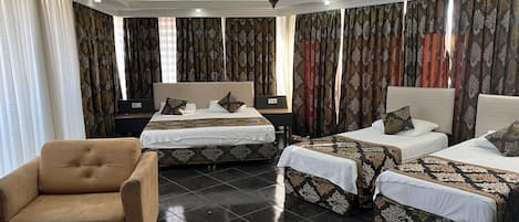 A hotel room with two beds, a sofa, a table, and a chandelier.