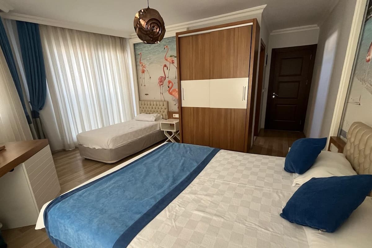 A hotel room with a bed, a desk, a wardrobe, and a painting of flamingos.