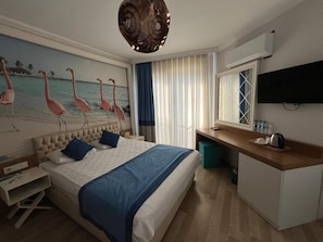 Una habitación de hotel con una cama, un escritorio, un televisor y un cuadro de flamencos.