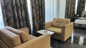 A hotel room with a sofa set, a small table, and a bed. - River Suite Otel (Manavgat)