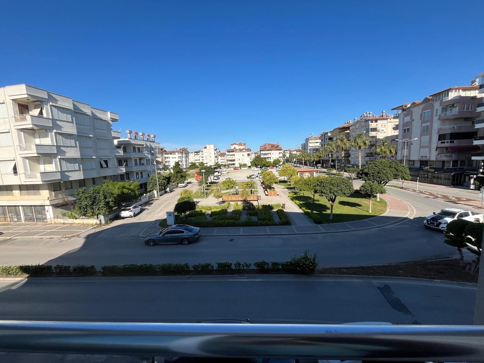 Una calle residencial con edificios de varios pisos, una rotonda en el centro y un coche estacionado al lado.