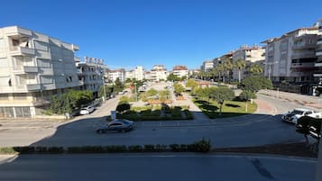 Una calle residencial con edificios de varios pisos, una rotonda en el centro y un coche estacionado al lado.