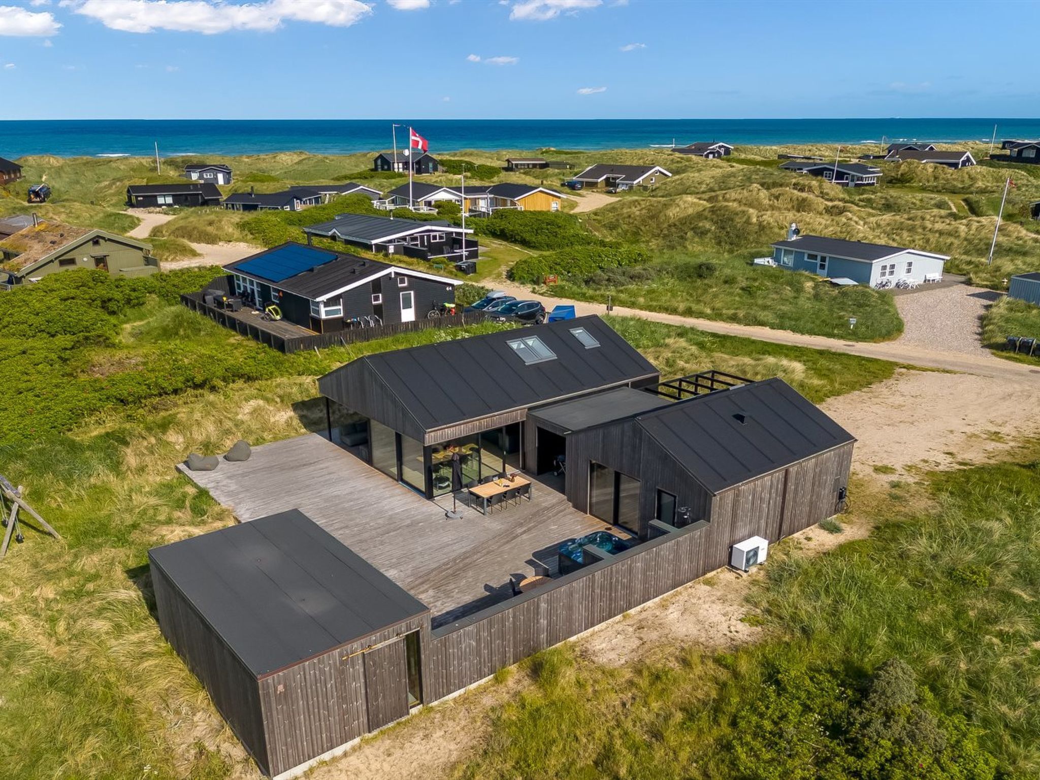 Une maison de plage moderne dotée d’une grande terrasse, d’une piscine et offrant une vue sur l’océan.