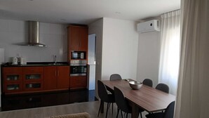Et moderne køkken med spiseplads, inklusive et bord og stole, samt en aircondition på væggen.