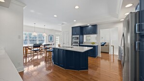 A modern kitchen with a central island, built-in appliances, and a dining area with wooden chairs. - 6-BR Waterfront House; Can Rent Boat Too! (Lake Norman of Catawba)