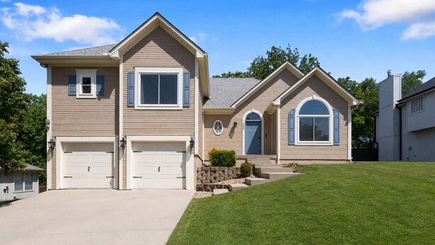 A two-story house with a garage, a front porch, and a well-maintained lawn.