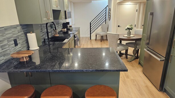 Eine moderne Küche mit Granit-Arbeitsplatten, Edelstahlgeräten und einer zentralen Kochinsel mit Hockern.