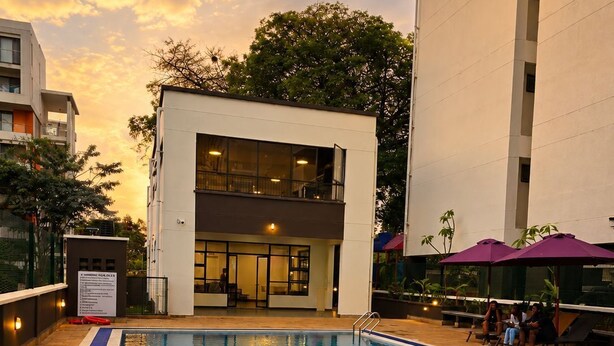 Una piscina con superficie de agua azul cristalina, rodeada por un edificio de techo plano y grandes ventanales.
