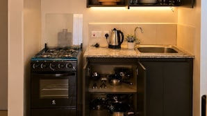 Una cocina moderna con estufa a gas, estanterías empotradas, cafetera y hervidor.