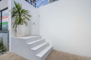 A white staircase leading to a door, a potted plant, and a white wall. - New1BR Villa Private Pool in Uluwatu (Kuta)