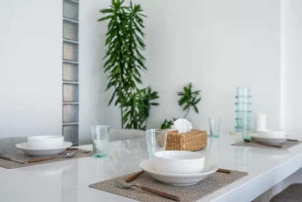 A dining table set with white plates, clear glasses, and a woven placemat. - New1BR Villa Private Pool in Uluwatu (Kuta)