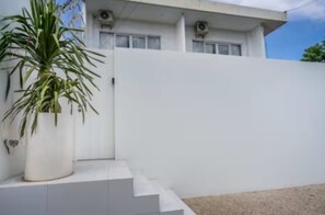 Ein modernes Gebäude mit weißer Fassade, einem Blumentopf vor der Treppe und blauem Himmel.