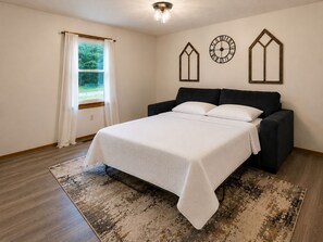 Ein Schlafzimmer mit einem Bett, einem Fenster mit Vorhängen, einer Wanduhr und einer dekorativen Wandgestalt.