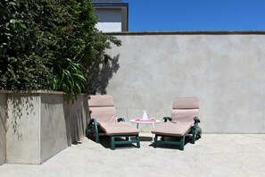 Two lounge chairs with a small table between them, a concrete wall, and a hedge. - La Maison Chopin - PLERIN (PLERIN)