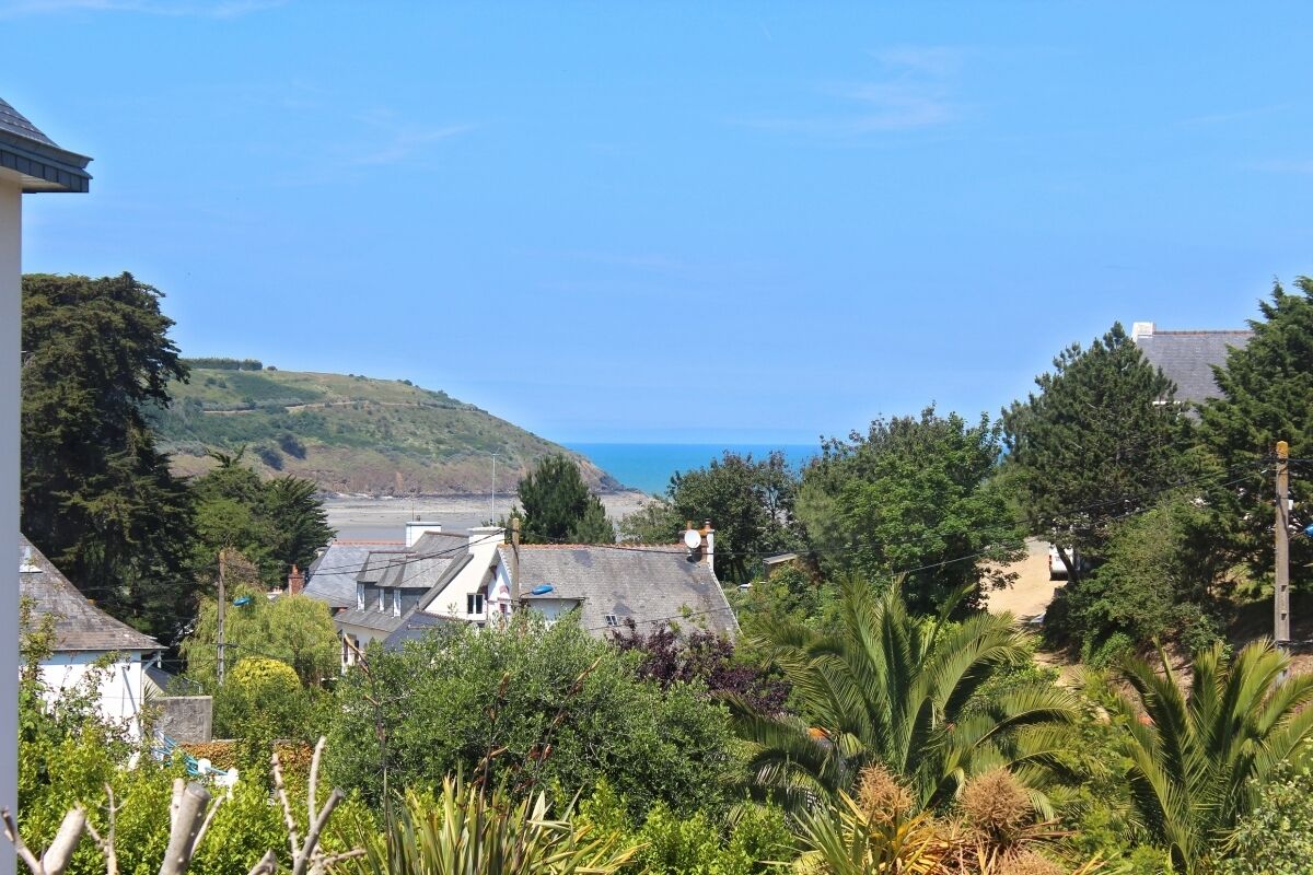A coastal residential area with houses, greenery, and a view of the sea.