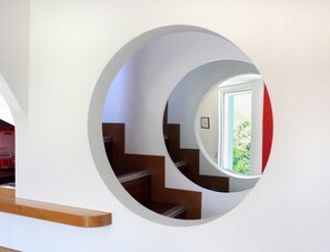 A circular mirror reflecting a staircase and a window with greenery outside. - La Maison Chopin - PLERIN (PLERIN)