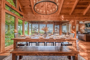 A wooden dining room with a large table set for six, large windows, and a chandelier. - Luxury Lodge*Stunning Views*Prime-Location*Arcade (Sevierville)