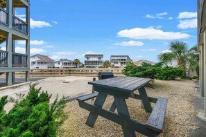 A beachside patio with a picnic table, a wooden deck, and houses in the background. - Sea Cabin 242- 2 Bedroom in Cherry Grove (North Myrtle Beach)
