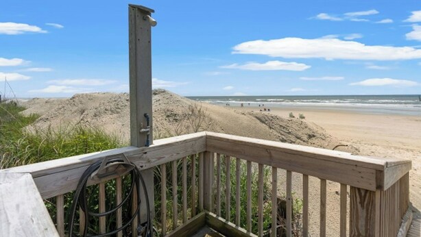 Een houten terras met uitzicht op een zandstrand en de oceaan.