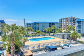 Ein Hotel mit Swimmingpool, Palmen und einem Parkplatz.
