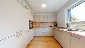 A modern kitchen with white cabinets, a wooden countertop, and a window providing natural light. - Modern, spacious house with 5 bedrooms, 3 bathrooms and a large garden (Kindsbach)