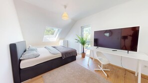 A modern bedroom with a bed, a desk, a TV, and a skylight. - Modern, spacious house with 5 bedrooms, 3 bathrooms and a large garden (Kindsbach)