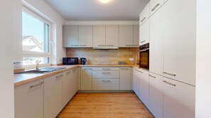 A compact kitchen with white cabinets, a microwave, a kettle, and a sink. - Modern, spacious house with 5 bedrooms, 3 bathrooms and a large garden (Kindsbach)