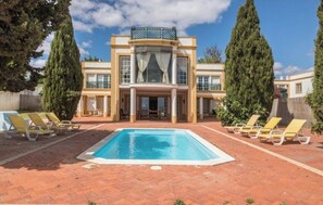 A large building with a swimming pool, multiple lounge chairs, and tall trees. - VILA Bouganvila - V3 - Jacuzzi in top of the Sea (Albufeira)