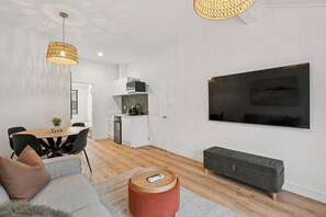 A modern apartment with a dining area, kitchenette, and a large TV mounted on the wall. - Melbourne Central| 2 BDRM walk to town (Queenstown)