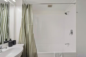 A bathroom with a shower, a sink, and a mirror. - Melbourne Central| 2 BDRM walk to town (Queenstown)