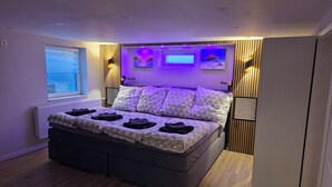 Quarto moderno com cama, abajures, janela e obra de arte na parede.