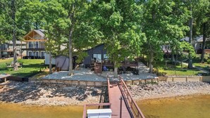 A lakeside property with a dock, a covered seating area, and a building with a deck.