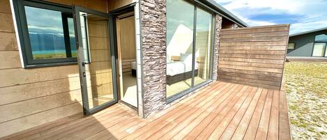 A modern house with a wooden deck, large glass doors, and a stone accent wall.