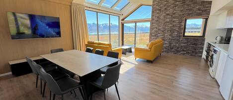 Un salon moderne avec un coin repas, de grandes fenêtres et un mur d’accent en pierre.