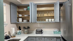 Eine Küche mit grauen Schränken, einem Edelstahlkühlschrank, einem Toaster und einer Kaffeestation.