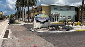 A sign for Barefoot Beach Resort with a clear sky and palm trees.