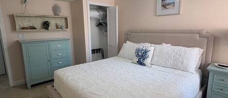 Un dormitorio con cama, ventilador de techo, mesita de noche, cómoda y armario.