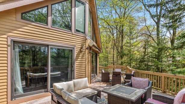 Eine Terrasse mit Gartenmöbeln, einer Glastür und einem Geländer aus Holz.