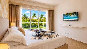 Een hotelkamer met een bed, een televisie, een raam met uitzicht op palmbomen en een schilderij aan de muur.