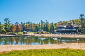 A lakeside view with a building, a small dock, and a grassy area. - Lake View Lodge/Hot Tub/Game Room/ Grill/Kayak (Lake Harmony)