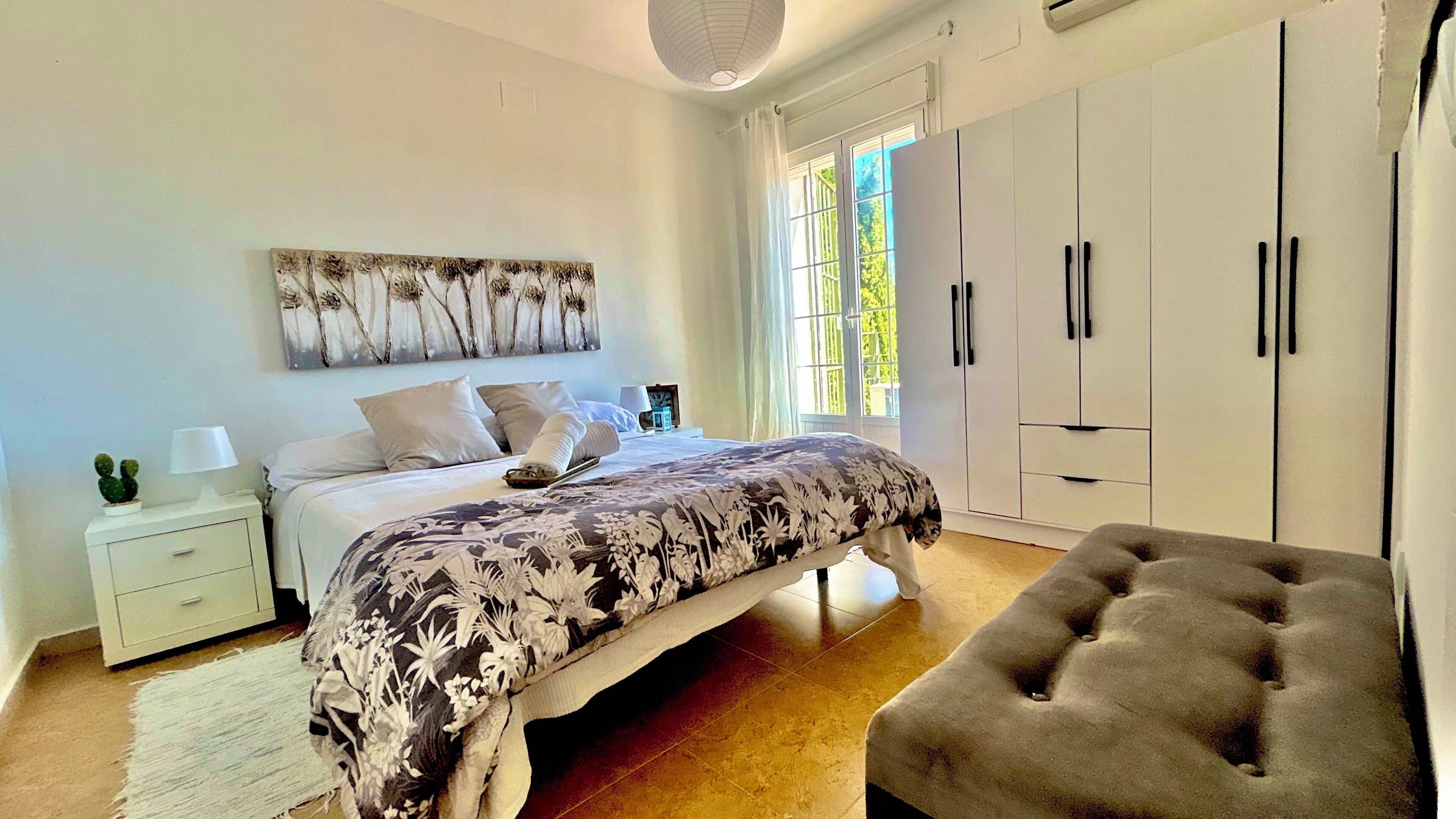 A bedroom with a bed, bedside table, lamp, and a chair.