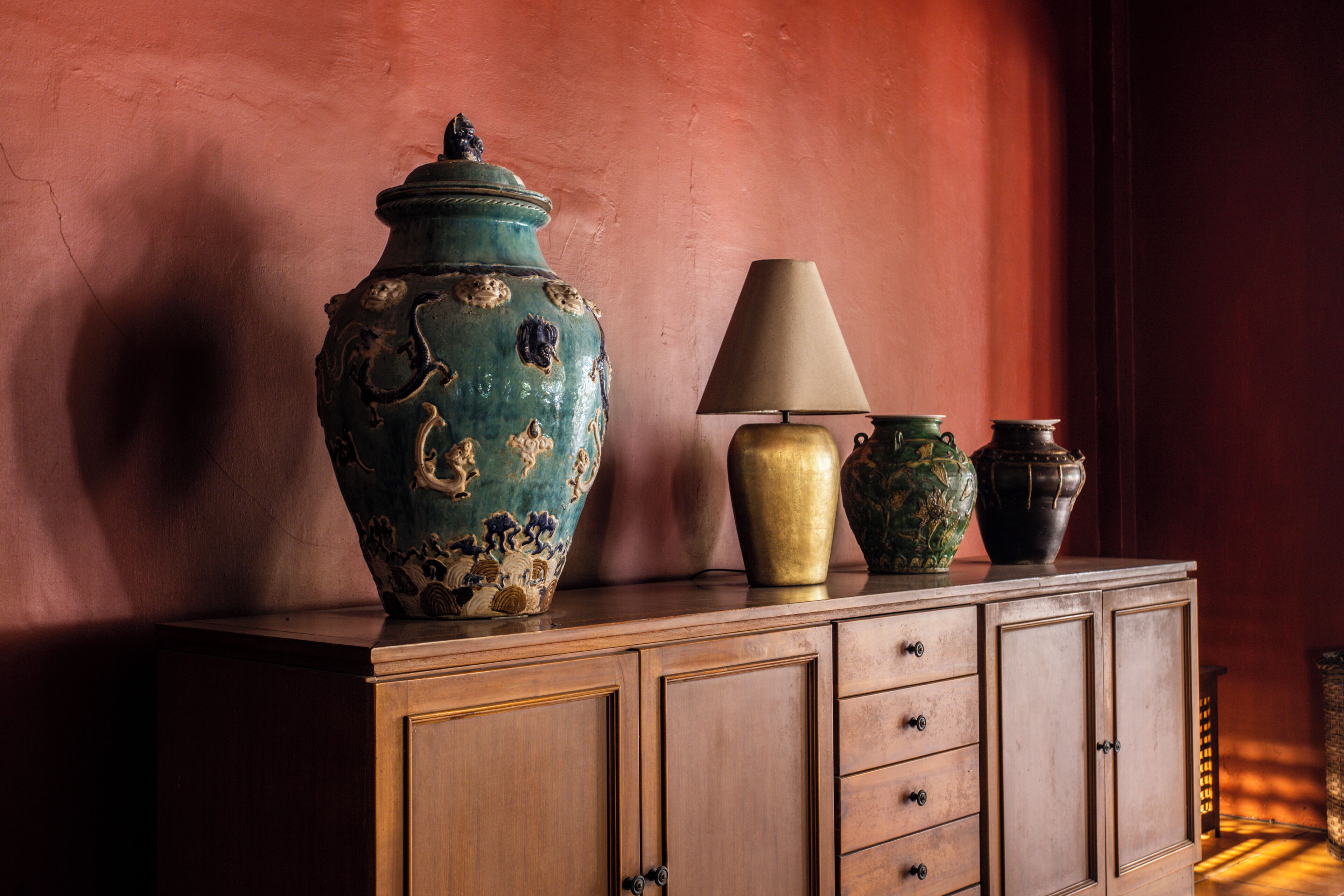 A wooden cabinet with decorative vases and a lamp.
