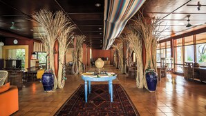 Un vestíbulo amplio con una mesa central, jarrones grandes y plantas decorativas altas.