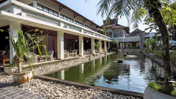 Un hotel con un espacio exterior techado, piscina y plantas en macetas.