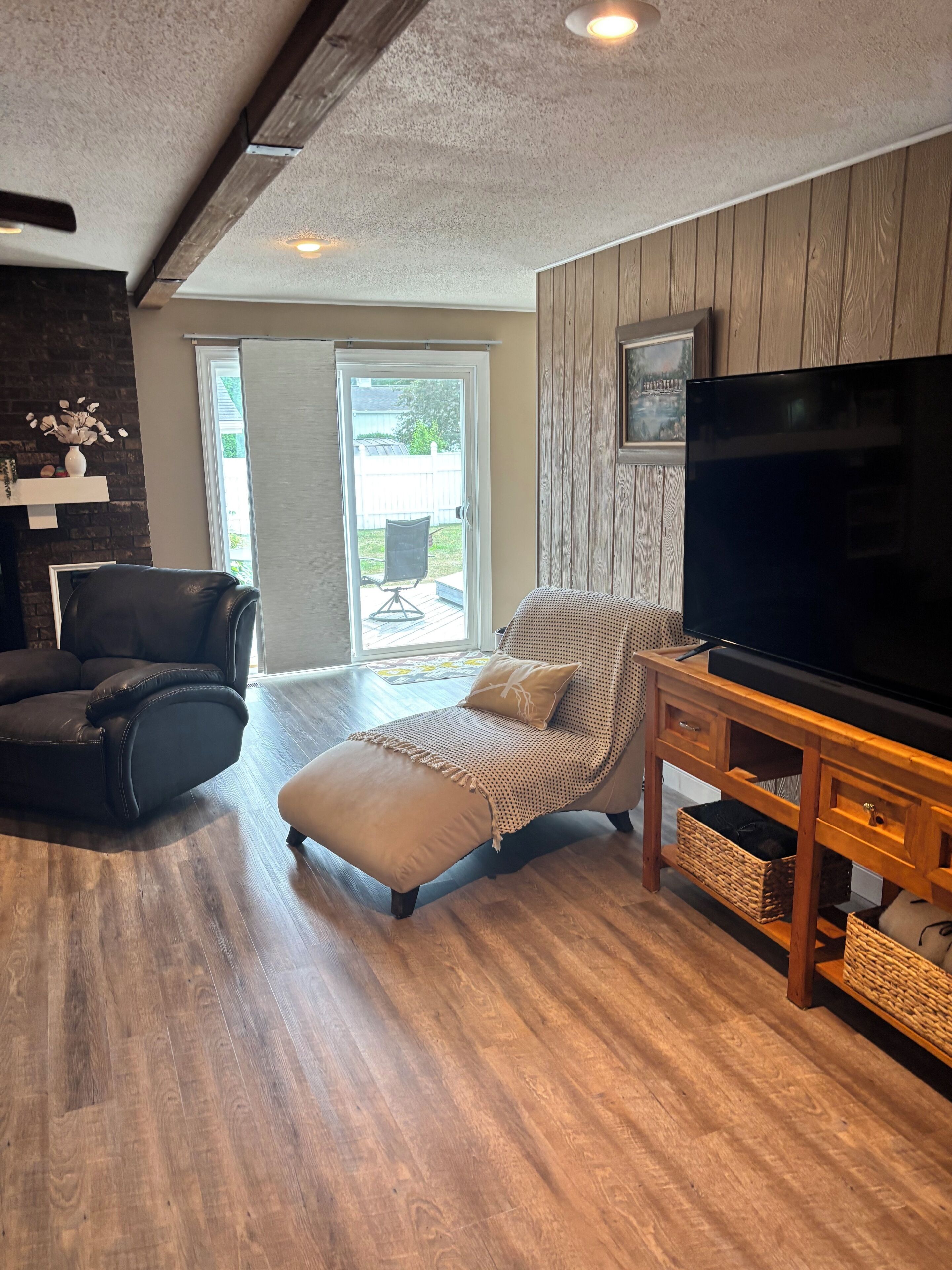 Un salon comprenant un canapé, un pouf, un meuble TV en bois et une cheminée.