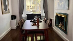 A dining area with a table, chairs, a fireplace, and a large window with curtains. - Spacious Home - Sleeps 5 Persons (Liverpool)
