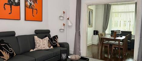 A living room with a black sofa, a coffee table, and two framed artworks on the wall.