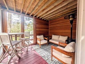 Ein Holzhütten-Innenraum mit einer Terrasse, einem Sofa, zwei Sesseln und einem Tisch.