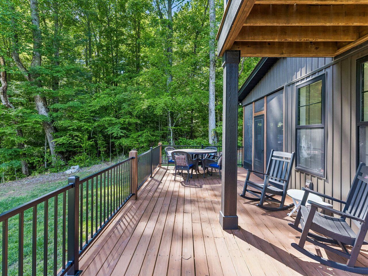 A wooden deck with outdoor furniture, surrounded by trees.