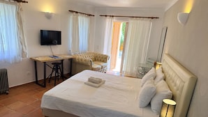 Un dormitorio con cama, escritorio, silla, televisor y lámpara.